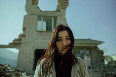 woman in white coat standing in front of a demolished building